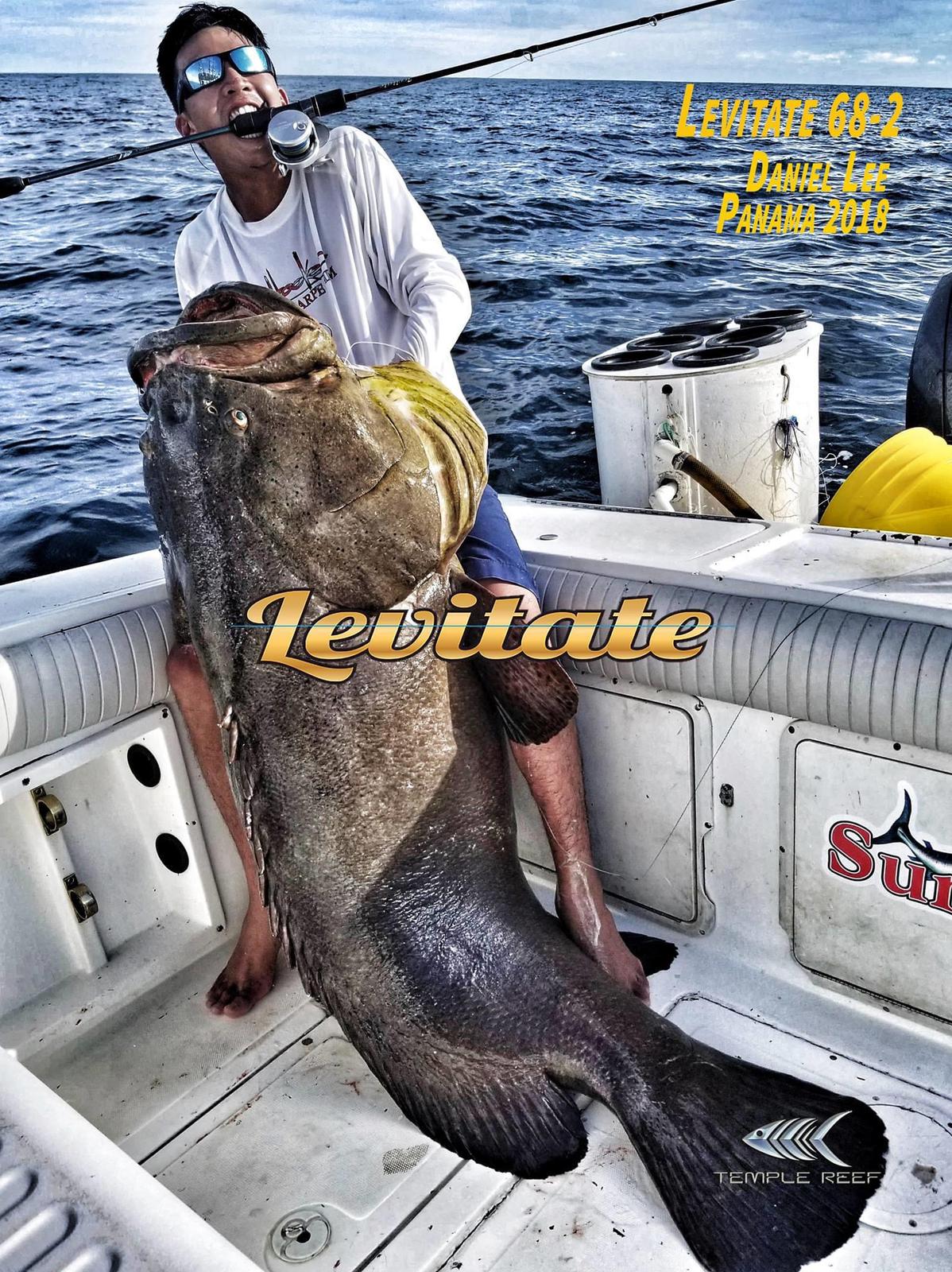 A man holding onto the back of a large fish.