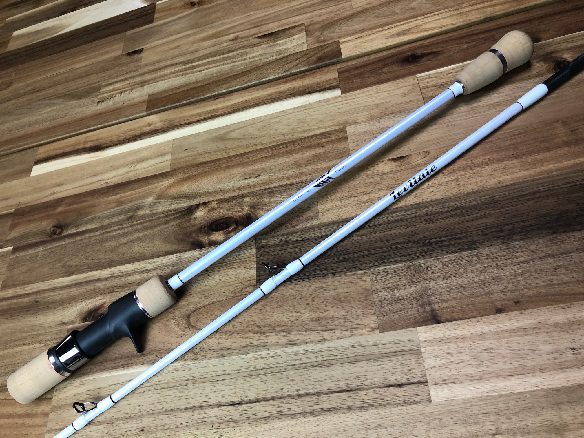 A pair of fishing rods sitting on top of a wooden floor.